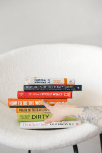 Books on healing, emotional intelligence, and empowerment—captured with a guiding hand—representing the role of personal story in branding.